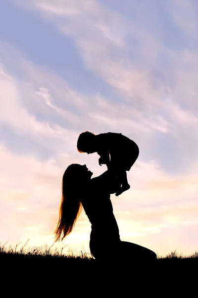 Silhouette di felice madre giocare fuori con bambino — Foto Stock