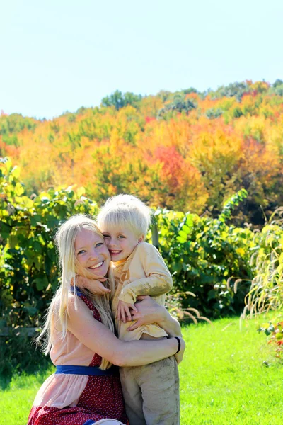 Mutter und Kind umarmen sich im Herbst-Apfelgarten — Stockfoto