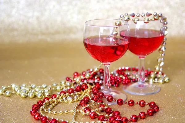 Copas de vino tinto y decoraciones de cuentas con fondo dorado — Foto de Stock