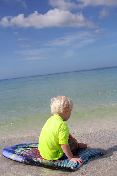 Niño pequeño sentado en Boogie Board en el océano —  Fotos de Stock