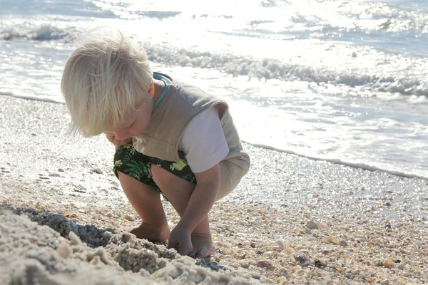 Jonge kind oppakken van schelpen op Beach door Oceaan — Stockfoto