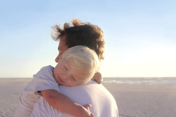 Unga barn vilar i fars armar på stranden — Stockfoto