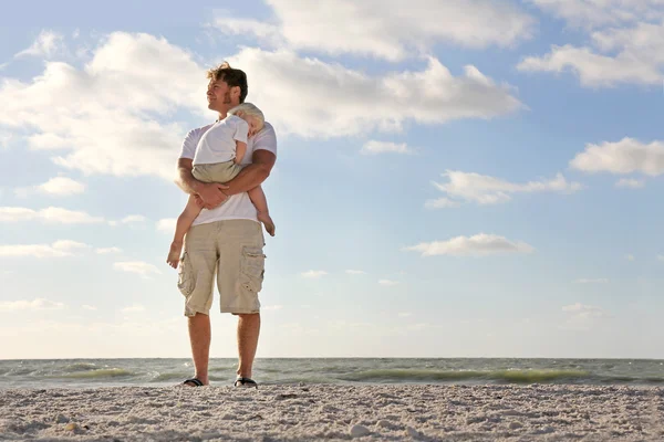 Jeune enfant se reposant dans les bras du père sur la plage par l'océan — Photo