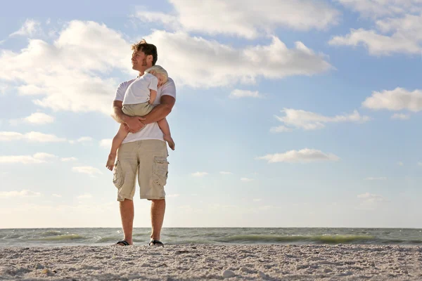 Young Child Resting in Father's Arms on Beach by Ocean — Stock Photo, Image