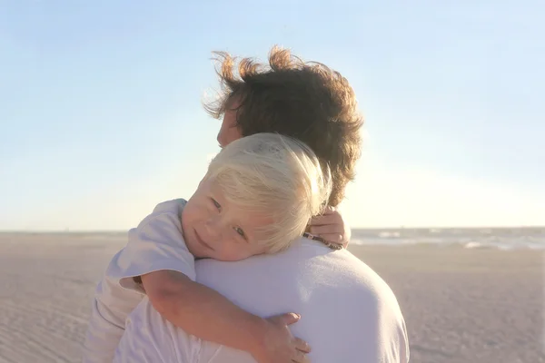Jeune enfant se reposant dans les bras du père sur la plage — Photo