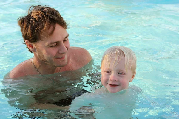 Отец учит маленького ребенка плавать в бассейне — стоковое фото
