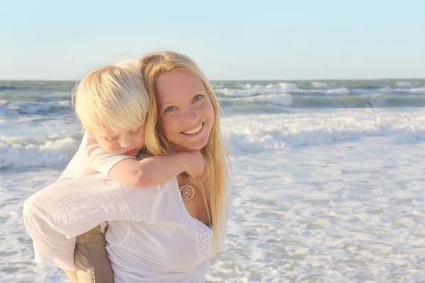 Moeder uitvoering jong kind Piggyback door oceaanwater — Stockfoto