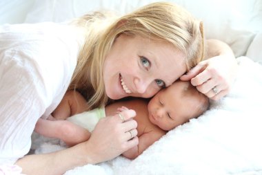 Happy Young Mother Snuggling her Newborn Baby Girl clipart