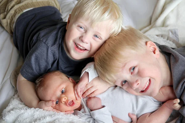 Hermanos grandes abrazando recién nacido bebé hermana —  Fotos de Stock