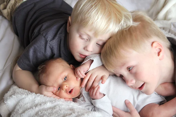 Hermanos grandes abrazando recién nacido bebé hermana — Foto de Stock