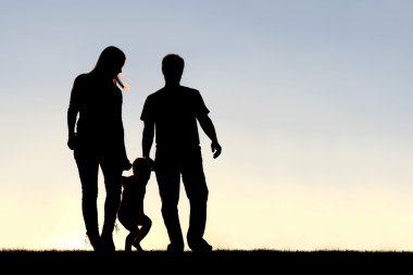 Gün batımında yürüyüş Üç Kişilik ailenin silüeti