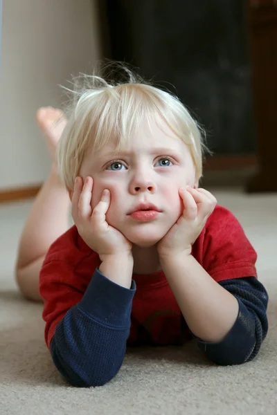 Adorable niño pequeño acostado en el piso del salón — Foto de Stock