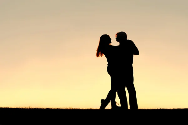 Silhouette eines glücklichen jungen Paares, das bei Sonnenuntergang tanzt — Stockfoto
