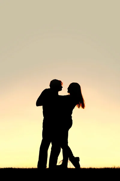 Silhueta de feliz jovem casal dançando ao pôr do sol — Fotografia de Stock