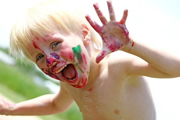 Niño joven feliz con la cara pintada desordenada — Foto de Stock