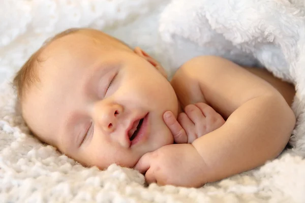 Lächelnd schlafendes neugeborenes Mädchen in weiße Decke gehüllt — Stockfoto