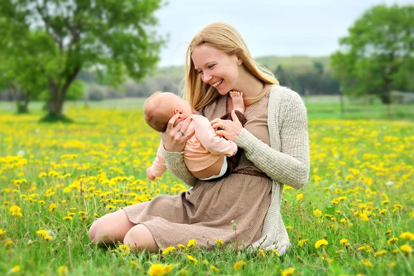 Feliz joven madre jugando con el bebé recién nacido fuera — Foto de Stock