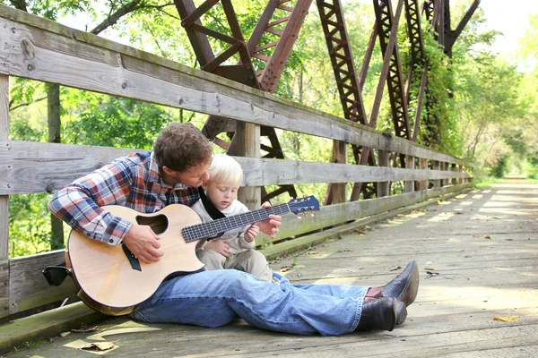 Vater und kleines Kind spielen draußen im Park Gitarre — Stockfoto