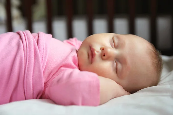Сладкая новорожденная девочка спит в детской кроватке — стоковое фото
