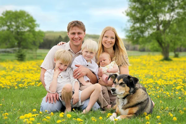 Glückliche Familie und Hund auf der Blumenwiese — Stockfoto