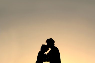 Genç çocuk alnından öpmek baba silüeti