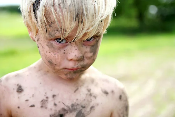 Грустный мальчик, покрытый грязью и грязью снаружи — стоковое фото
