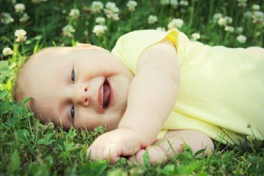 Laughing Newborn Baby Laying in Grass OUtside clipart