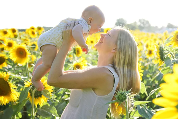 Gelukkig moeder en Baby dochter in zonnebloem veld — Stockfoto