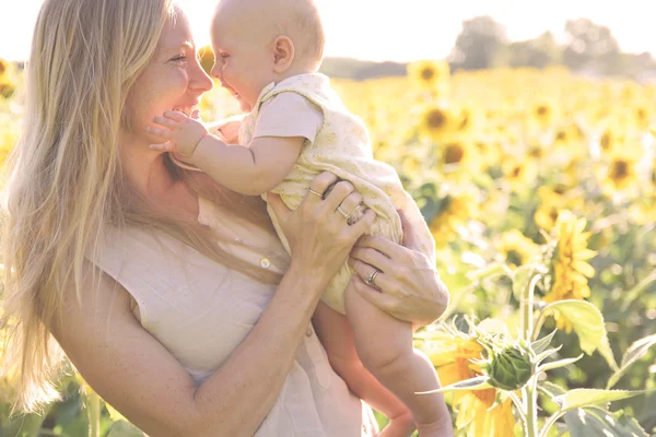 Feliz madre e hija en el campo de girasol — Foto de Stock