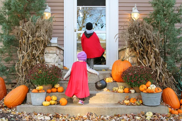 Kinder in Umhang-Kostümen tricksen oder behandeln an Halloween — Stockfoto