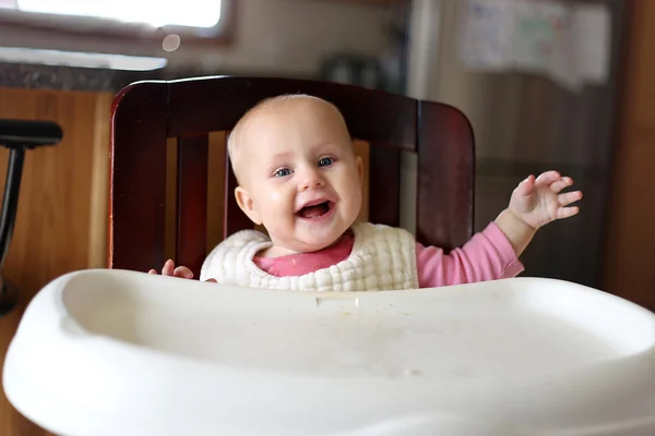 Feliz bebé de 6 meses en babero comiendo en la silla alta —  Fotos de Stock