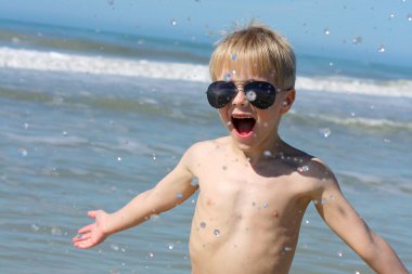 Okyanusta oynayan mutlu genç çocuk