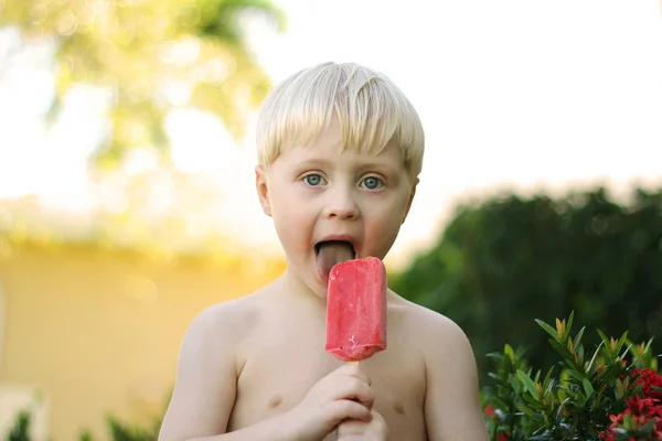 Niño lamiendo paleta de fruta de fresa — Foto de Stock