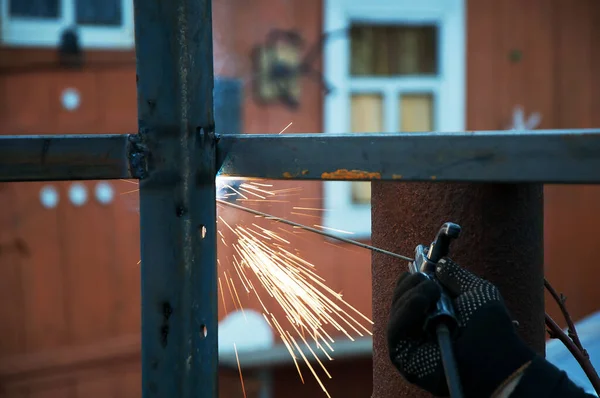 Welding work on the street. The welder will produce metal parts on the site. welding of the metal frame, the work takes place on the street, the metal welding process is visible in close-up.