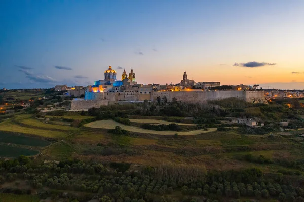 Mdina şehri - Malta 'nın eski başkenti. Akşam, doğa manzarası, günbatımı gökyüzü. Şehirde renkli ışıklar var.