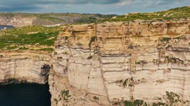 Malta kırsalının insansız hava aracı görüntüsü, doğa. Gozo adasındaki uçurumlar, Malta adasının bir parçası. Yeşil alanlar, kayalar ve kayalıklar