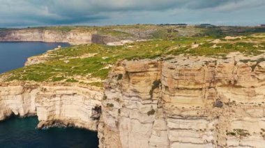 Malta kırsalının insansız hava aracı görüntüsü, doğa. Gozo adasındaki uçurumlar, Malta adasının bir parçası. Yeşil alanlar, kayalar ve uçurumlar. Akdeniz