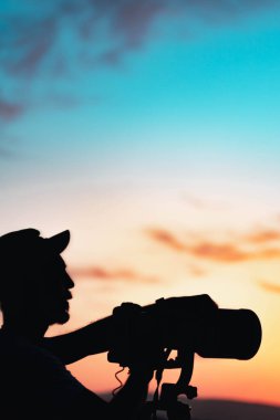 Gün batımında ayın altında çalışan vahşi yaşam fotoğrafçısının silueti. Yüksek kalite fotoğraf
