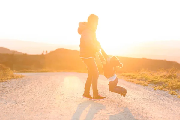Mutter und Kind spielen Sonnenuntergang auf dem Feld — Stockfoto