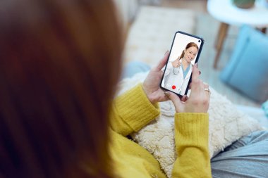 Evden bir kadın video konferansında doktoruna danışıyor.