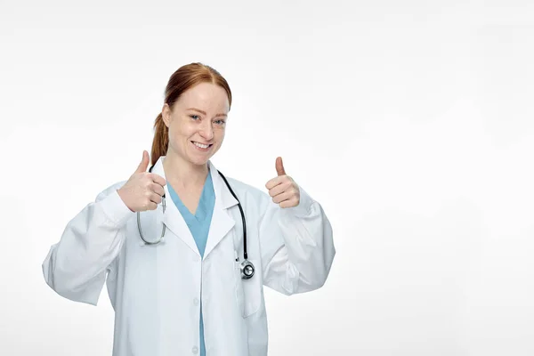 Νεαρή χαμογελαστή γυναίκα γιατρός κάνει αντίχειρες επάνω τους αντίχειρες επάνω σημάδι — Φωτογραφία Αρχείου