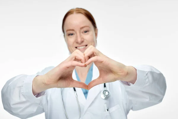 Giovane sorridente medico femminile che fa segno di cuore con le mani — Foto Stock