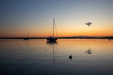Old Leigh, Leigh-on-Sea, Essex, İngiltere 'de günbatımına karşı teknelerin yansımaları. 
