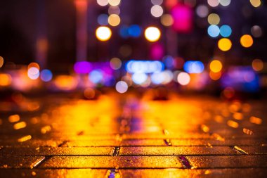 Şehirde yağmurlu bir gece. Pencerelerden gelen ışık 