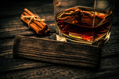 Bir bardak brendi ve jüt halatla bağlanmış tarçın çubukları.