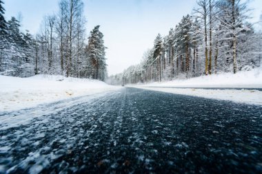 Kış günü kar yağar, araba yol boyunca gider.  
