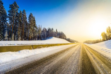 Açık bir kış sabahında gün doğumu, karda boş otoyollar.  
