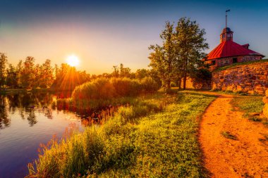 Nehir kıyısındaki ortaçağ kalesi. Gün batımı. Orman. Mavi gökyüzü.