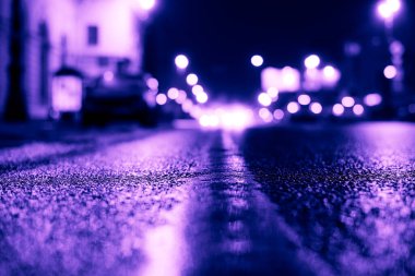 Park yerindeki alışveriş merkezinde yağmurlu bir gece, sıra sıra park edilmiş arabalar..