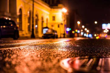 Büyük şehirde yağmurlu bir gece, su birikintileri olan boş bir yol.